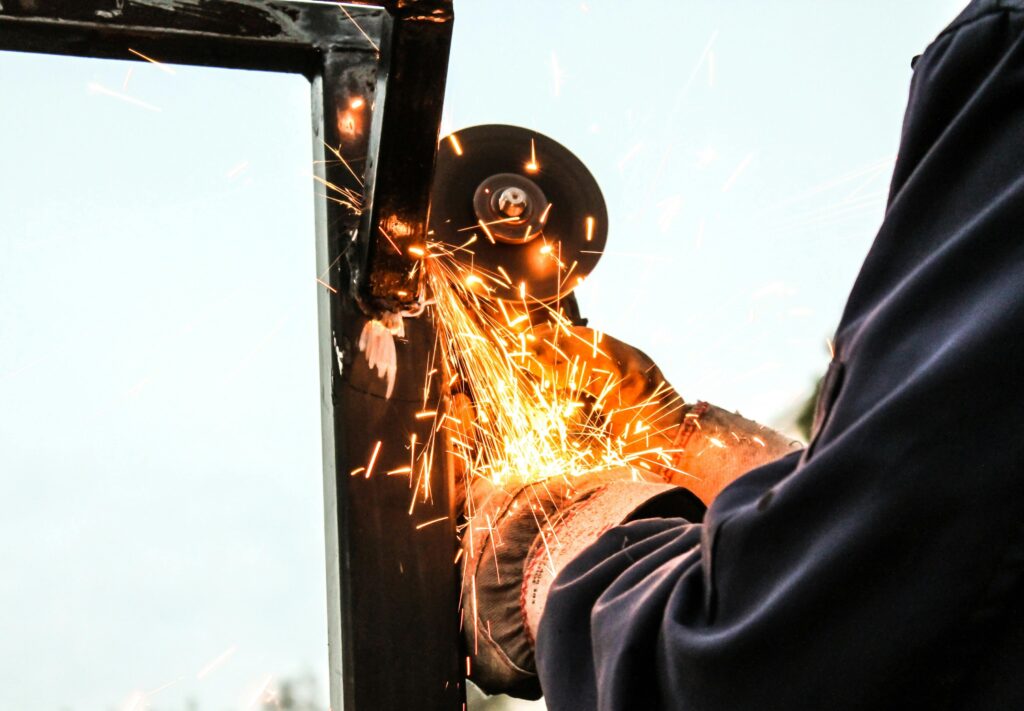 Close-up of a worker grinding metal outside creating dynamic sparks.