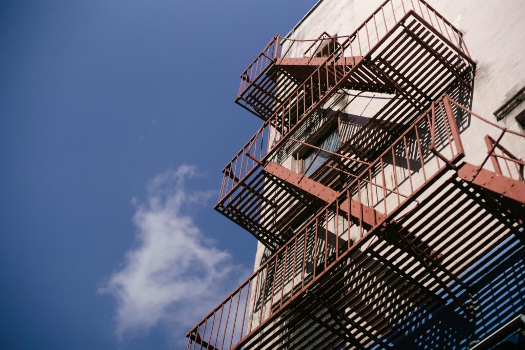 An industrial fire escape contrasts with a clear blue sky, showcasing urban architecture.